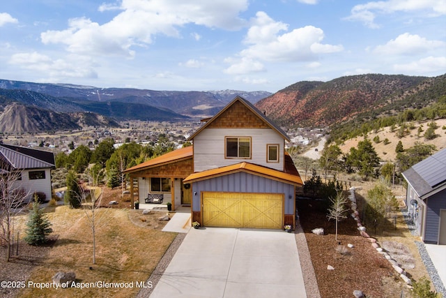 view of front of house with concrete driveway, a mountain view, an attached garage, and board and batten siding