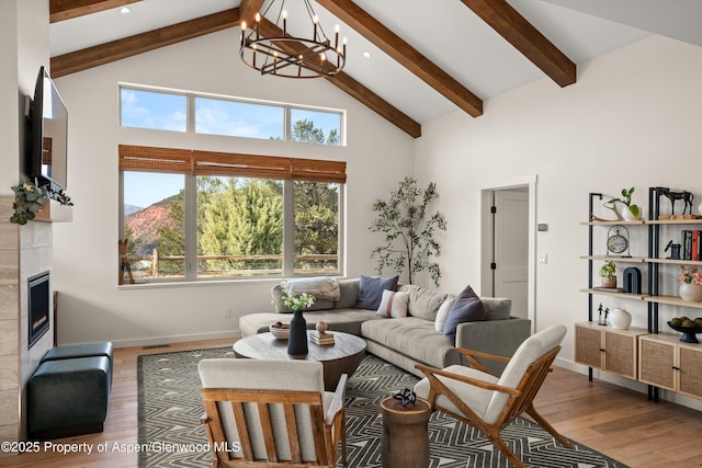 living area with high vaulted ceiling, wood finished floors, a fireplace, baseboards, and a chandelier