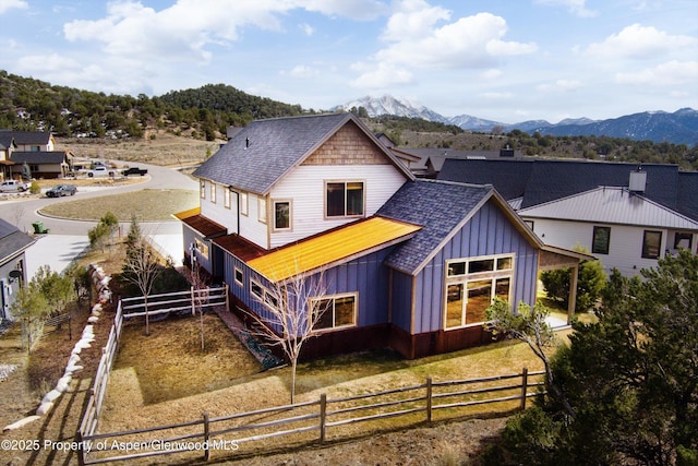 rear view of house with a mountain view, fence private yard, board and batten siding, and a shingled roof