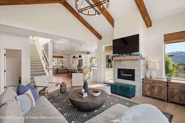 living area with high vaulted ceiling, a healthy amount of sunlight, a chandelier, and light wood finished floors