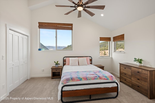 bedroom featuring a closet, vaulted ceiling, light colored carpet, and multiple windows