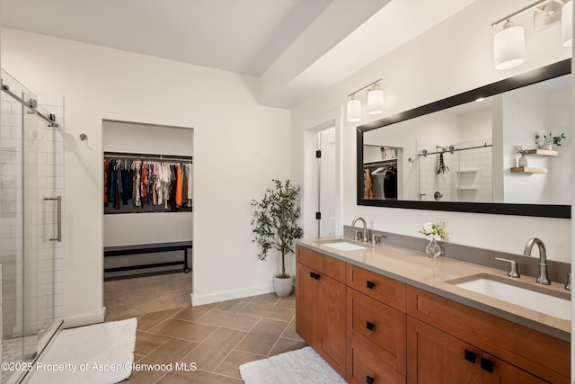 full bath with double vanity, a spacious closet, a stall shower, and a sink