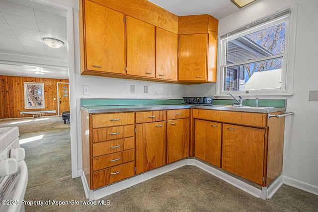 kitchen with dark colored carpet, brown cabinets, plenty of natural light, and wooden walls