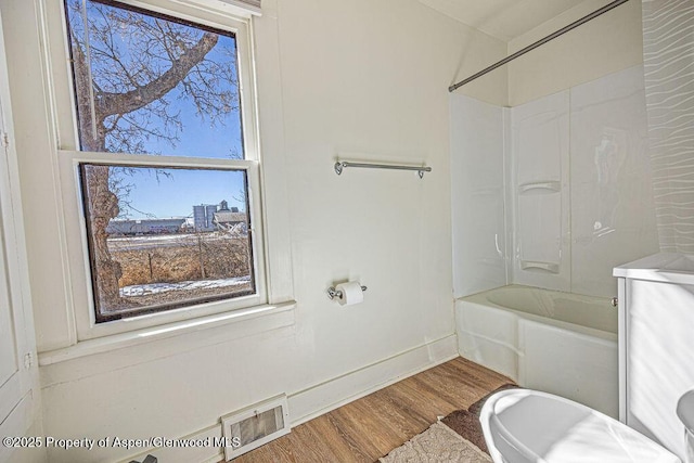 bathroom with  shower combination, wood finished floors, visible vents, and baseboards