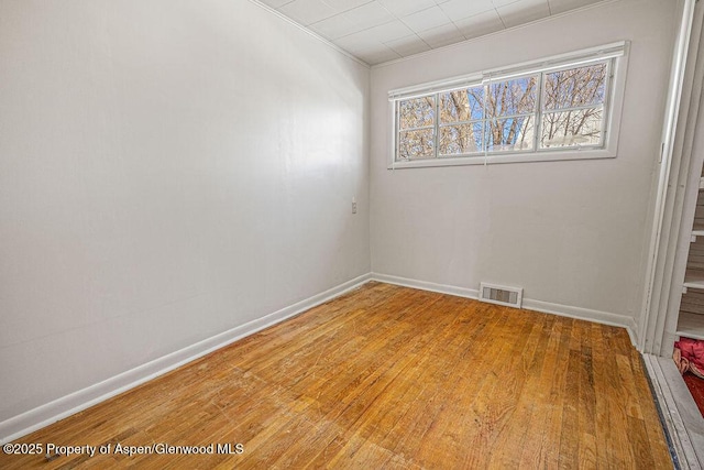 empty room featuring visible vents, light wood-style flooring, and baseboards