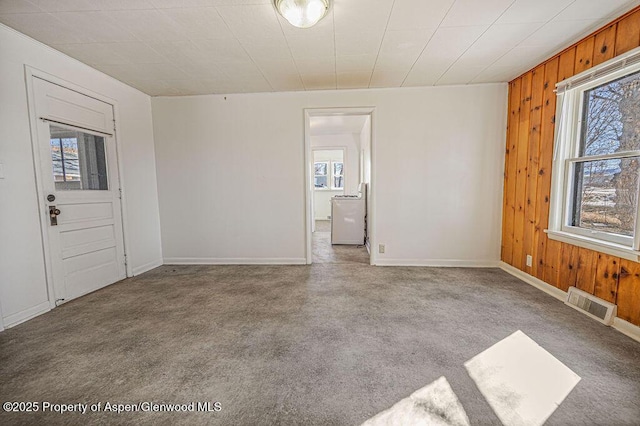 interior space with washer / dryer, wood walls, visible vents, and baseboards