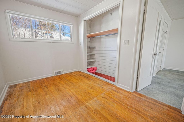 interior space with baseboards, wood-type flooring, visible vents, and a closet