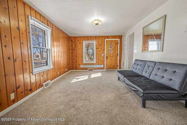 interior space with carpet floors, wood walls, visible vents, and baseboards