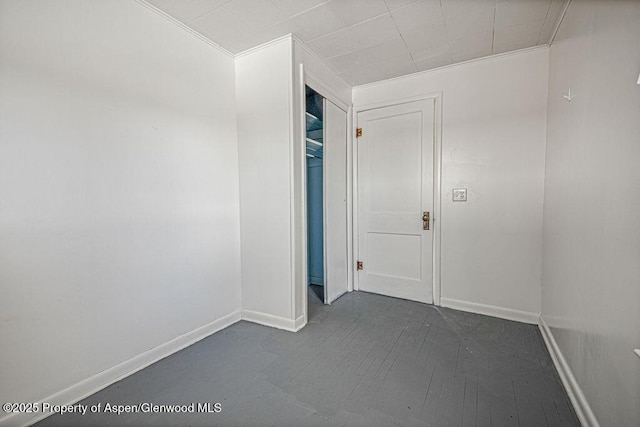 unfurnished room featuring dark wood-style floors, baseboards, and ornamental molding