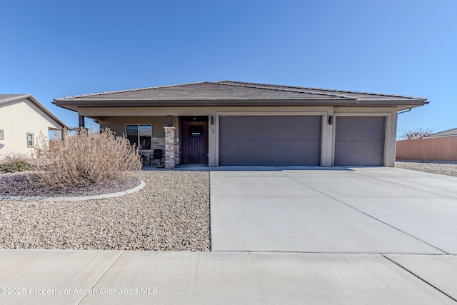 1326 Fairway Dr, Fruita, CO 81521 - view of front of home featuring driveway, stone siding, an attached garage, and stucco siding