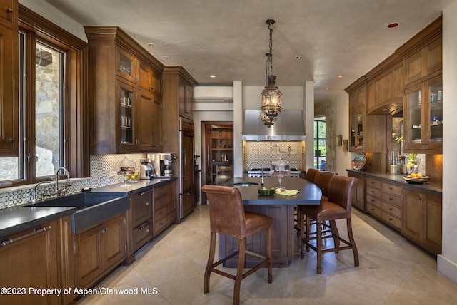 kitchen featuring backsplash, sink, hanging light fixtures, paneled built in refrigerator, and a breakfast bar area