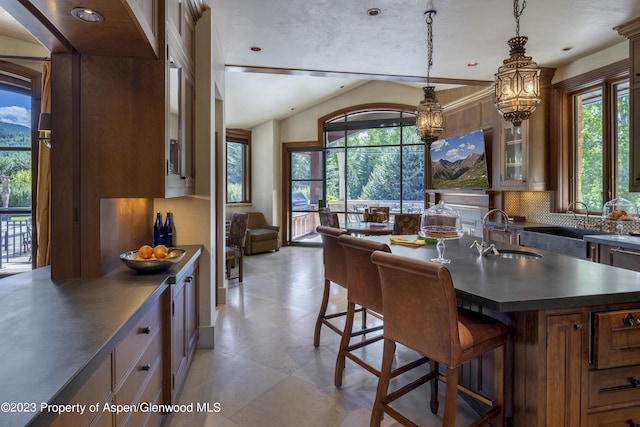 kitchen featuring sink, pendant lighting, a kitchen bar, decorative backsplash, and a kitchen island