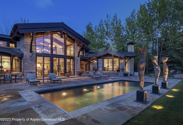 back house at dusk featuring a patio