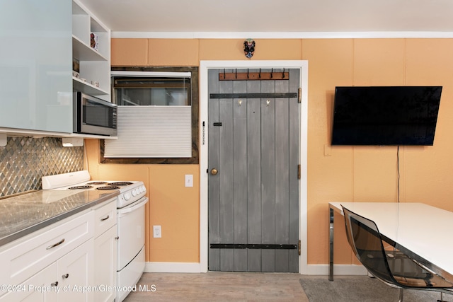 kitchen featuring decorative backsplash, light wood-type flooring, dark stone counters, white range with electric cooktop, and white cabinetry