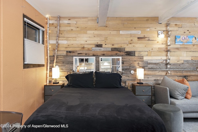 bedroom with beam ceiling and wood walls