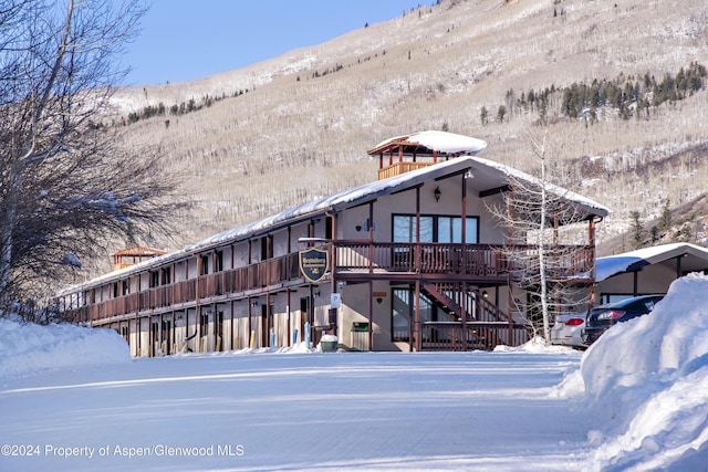 snow covered house with a deck with mountain view