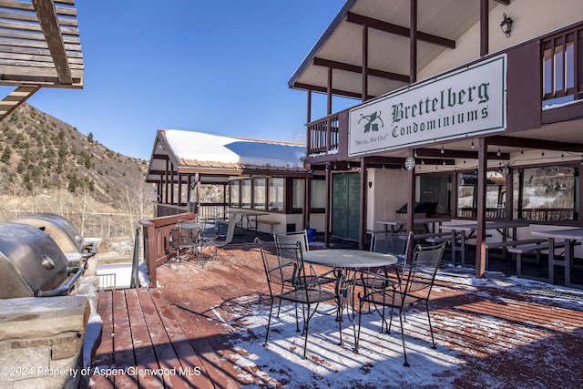 snow covered deck with area for grilling and a mountain view