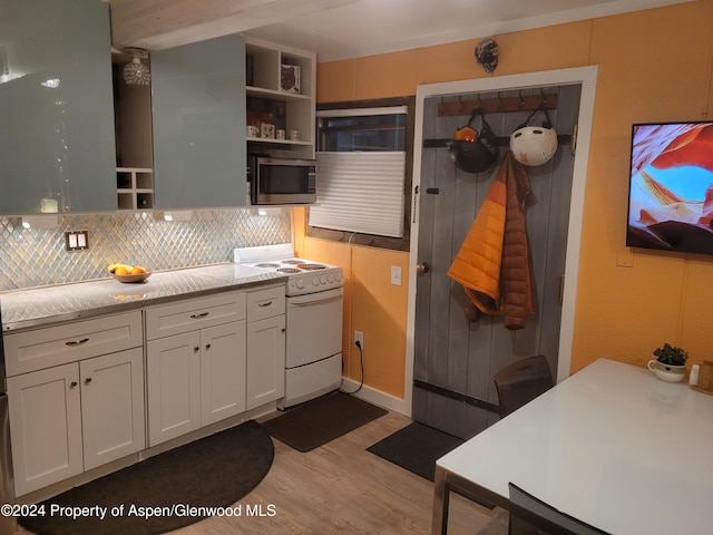 kitchen featuring white cabinetry, light stone countertops, white range oven, light hardwood / wood-style floors, and decorative backsplash