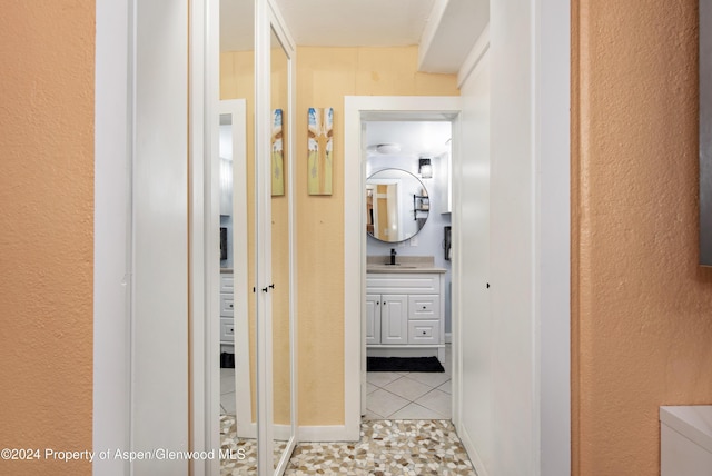 hall featuring light tile patterned floors and sink