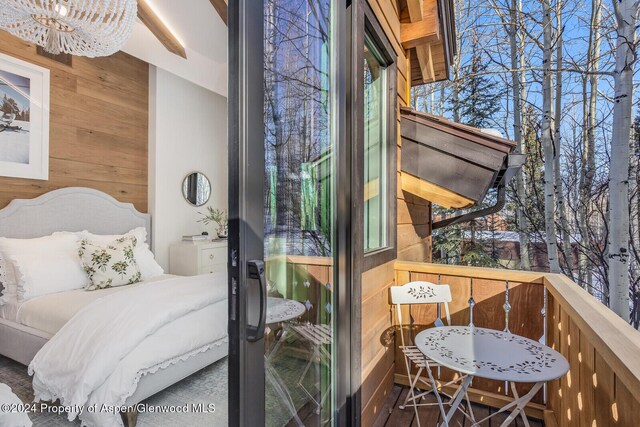 bedroom featuring an inviting chandelier, multiple windows, and wooden walls