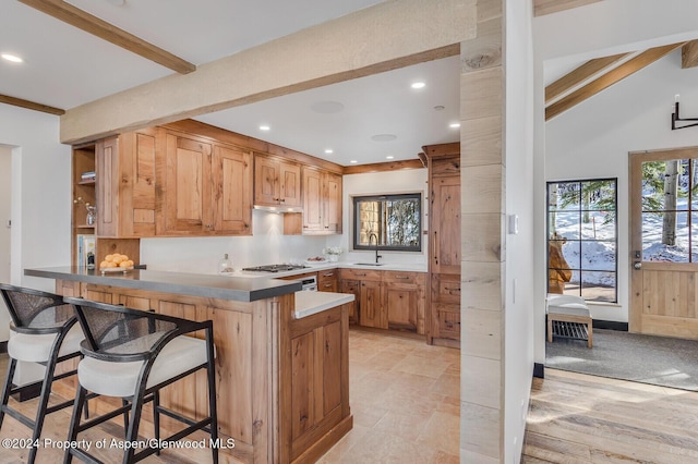 kitchen with kitchen peninsula, sink, high vaulted ceiling, beamed ceiling, and a breakfast bar area