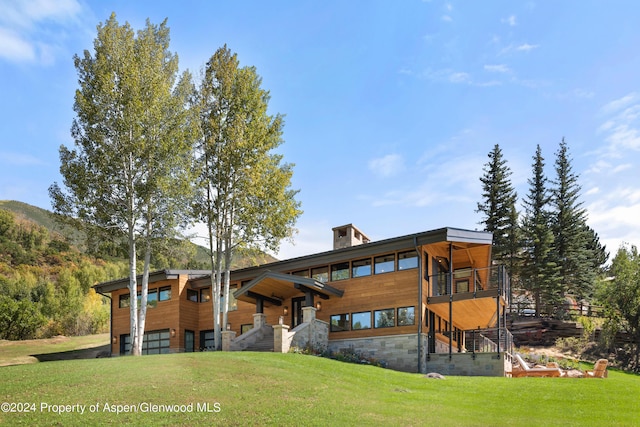 exterior space with stairway, stone siding, a lawn, a mountain view, and a garage