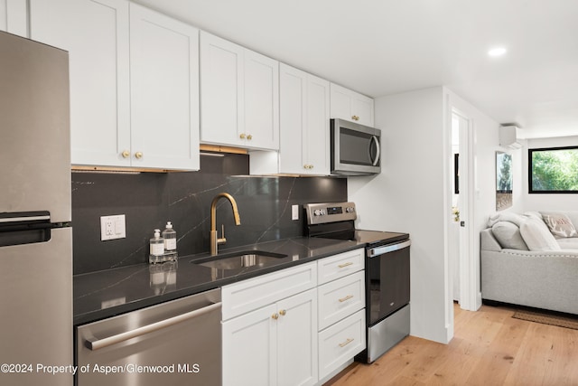 kitchen featuring stainless steel appliances, a wall unit AC, a sink, decorative backsplash, and open floor plan