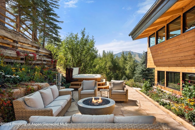 view of patio / terrace featuring an outdoor living space with a fire pit, a hot tub, and a mountain view