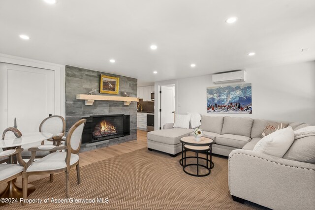 living room with a wall mounted air conditioner, recessed lighting, wood finished floors, and a fireplace