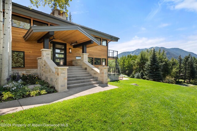 exterior space featuring stone siding, a front yard, and a mountain view