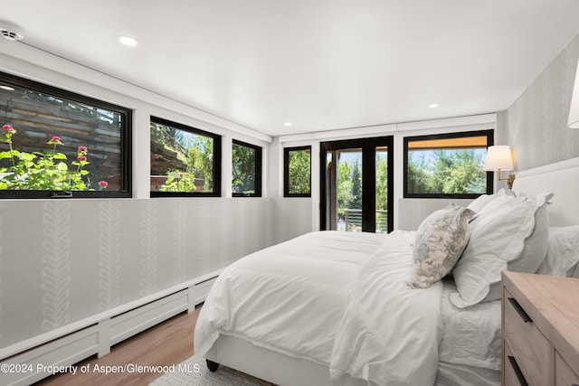bedroom with a baseboard heating unit, wood finished floors, and recessed lighting
