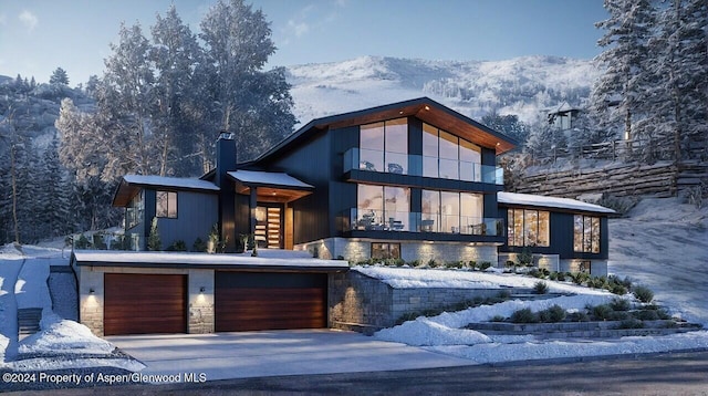 contemporary house with stone siding, a mountain view, and concrete driveway