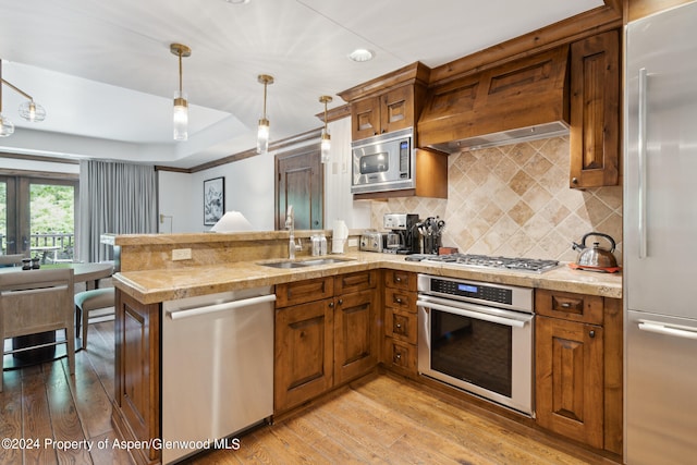 415 E Dean St Unit 32, Aspen, CO 81611 - kitchen featuring built in appliances, a sink, brown cabinetry, a peninsula, and light wood-style floors