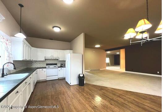 kitchen with white appliances, decorative light fixtures, white cabinetry, and sink