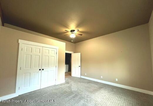 unfurnished bedroom featuring carpet floors, a closet, and ceiling fan