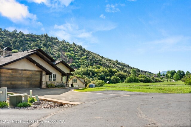 13 Laird Ln, Glenwood Springs, CO 81601 - view of front facade with a mountain view, an attached garage, stone siding, driveway, and stucco siding