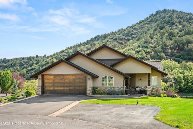 13 Laird Ln, Glenwood Springs, CO 81601 - view of front of house featuring stucco siding, a garage, a front lawn, driveway, and a mountain view