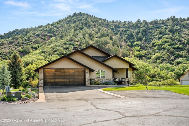 13 Laird Ln, Glenwood Springs, CO 81601 - view of front of property with stone siding, stucco siding, asphalt driveway, an attached garage, and a view of trees