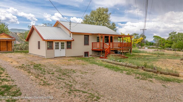 456 County Road 294, Rifle, CO 81650 - rear view of house with metal roof, a wooden deck, driveway, and french doors