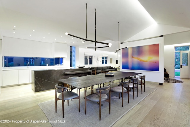 dining area featuring an inviting chandelier, lofted ceiling, and light wood-type flooring