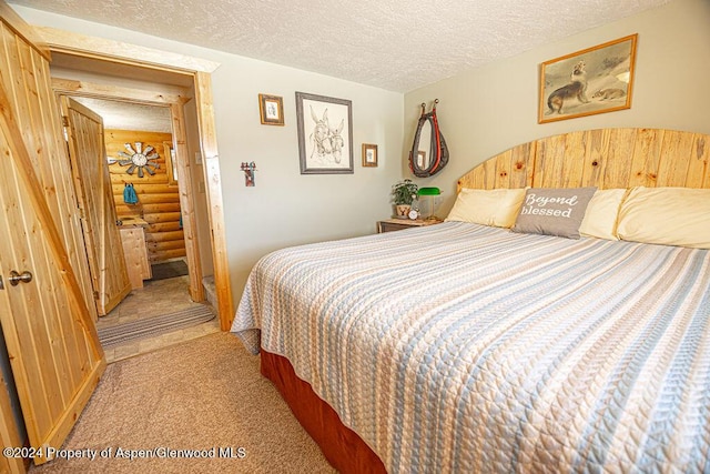 1020 Thompson Way, Craig, CO 81625 - bedroom with log walls, a textured ceiling, and light colored carpet