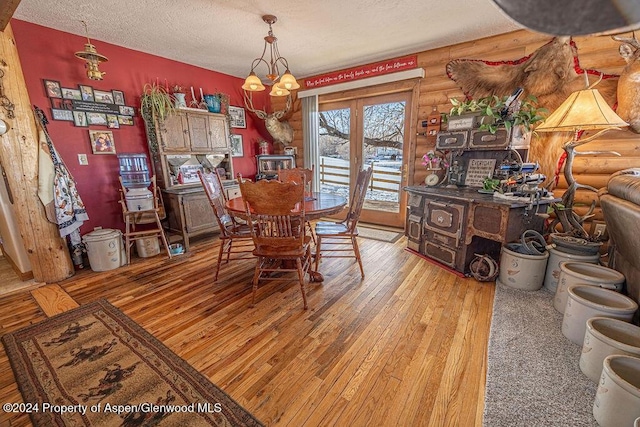 1020 Thompson Way, Craig, CO 81625 - dining room featuring log walls, hardwood / wood-style flooring, a textured ceiling, and a notable chandelier