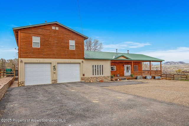 1020 Thompson Way, Craig, CO 81625 - view of front of property featuring a garage, aphalt driveway, fence, stone siding, and a porch