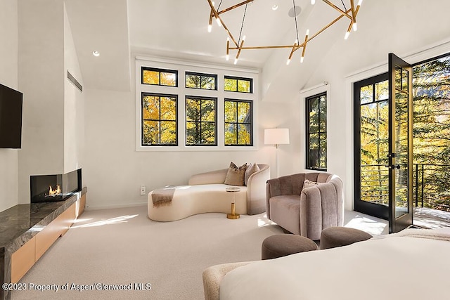 carpeted bedroom with a multi sided fireplace, multiple windows, a chandelier, and access to exterior