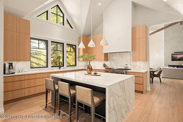 kitchen with a kitchen bar, a center island, high vaulted ceiling, and hanging light fixtures