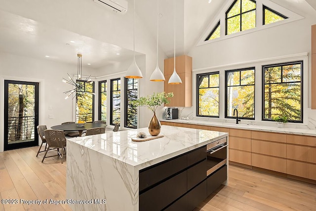 kitchen with a wall unit AC, a center island, hanging light fixtures, and sink