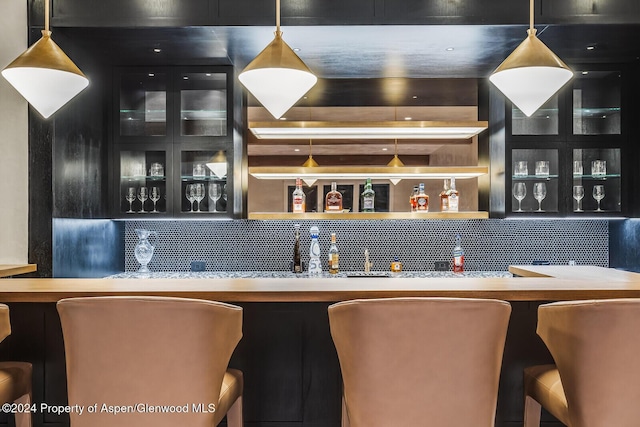 bar with decorative backsplash and hanging light fixtures