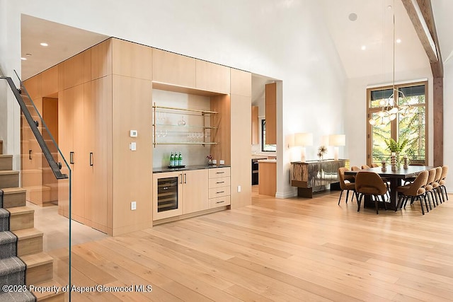 kitchen featuring beverage cooler, light wood-type flooring, beam ceiling, and high vaulted ceiling