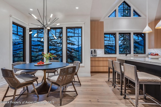 dining area with light wood-type flooring, sink, and a chandelier