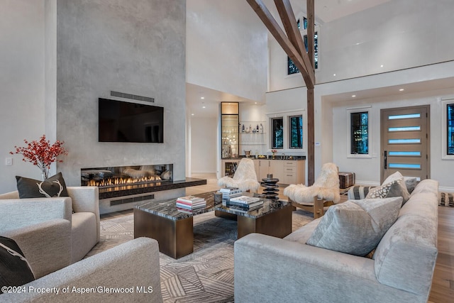 living room featuring a large fireplace, light hardwood / wood-style floors, and a high ceiling